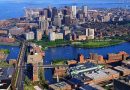 Aerial view of Boston showcasing its bustling downtown area with dense clusters of modern high-rises, the serene Charles River, and the intricate network of roads and bridges connecting diverse neighborhoods.