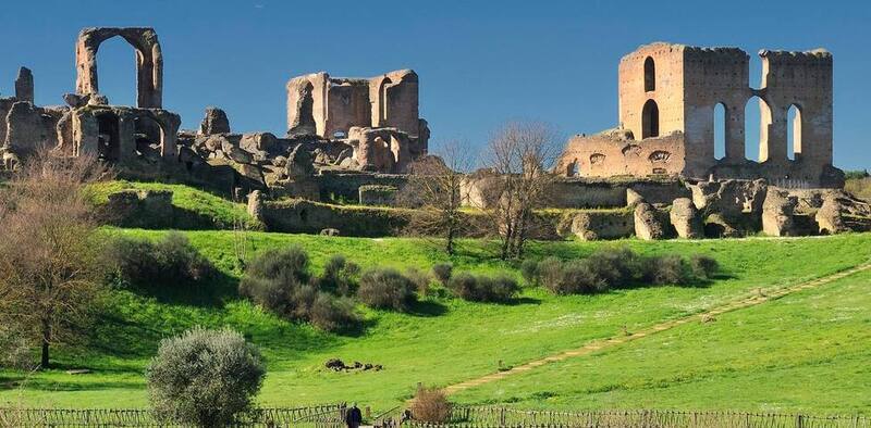 Ruins of Villa dei Quintili against green hills in Rome.